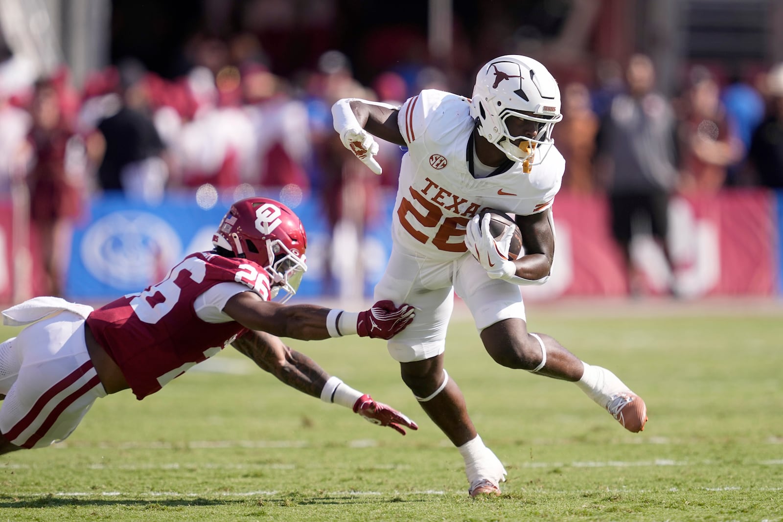 Texas running back Quintrevion Wisner (26) escapes a tackle attempt by Oklahoma defensive back Kani Walker (26) in the first half of an NCAA college football game in Dallas, Saturday, Oct. 12, 2024. (AP Photo/Tony Gutierrez)