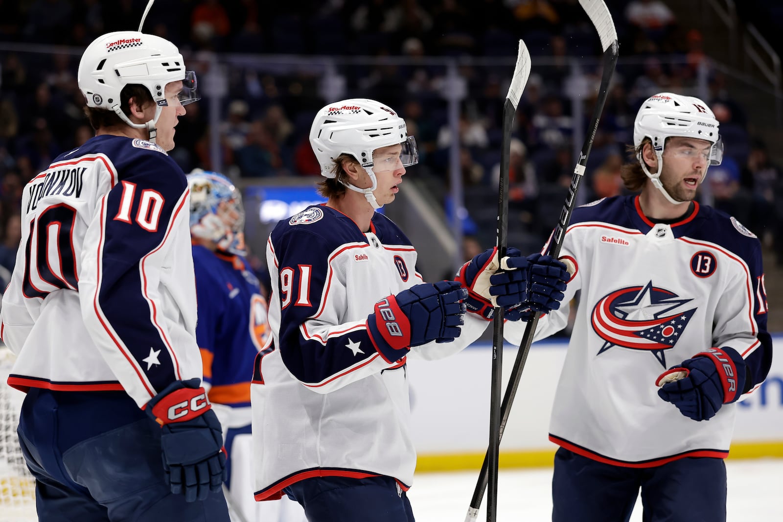 Columbus Blue Jackets center Kent Johnson (91) is congratulated by Adam Fantilli, right, and Dmitri Voronkov (10) after scoring in the first period of an NHL hockey game against the New York Islanders, Monday, Jan. 20, 2025, in Elmont, N.Y. (AP Photo/Adam Hunger)