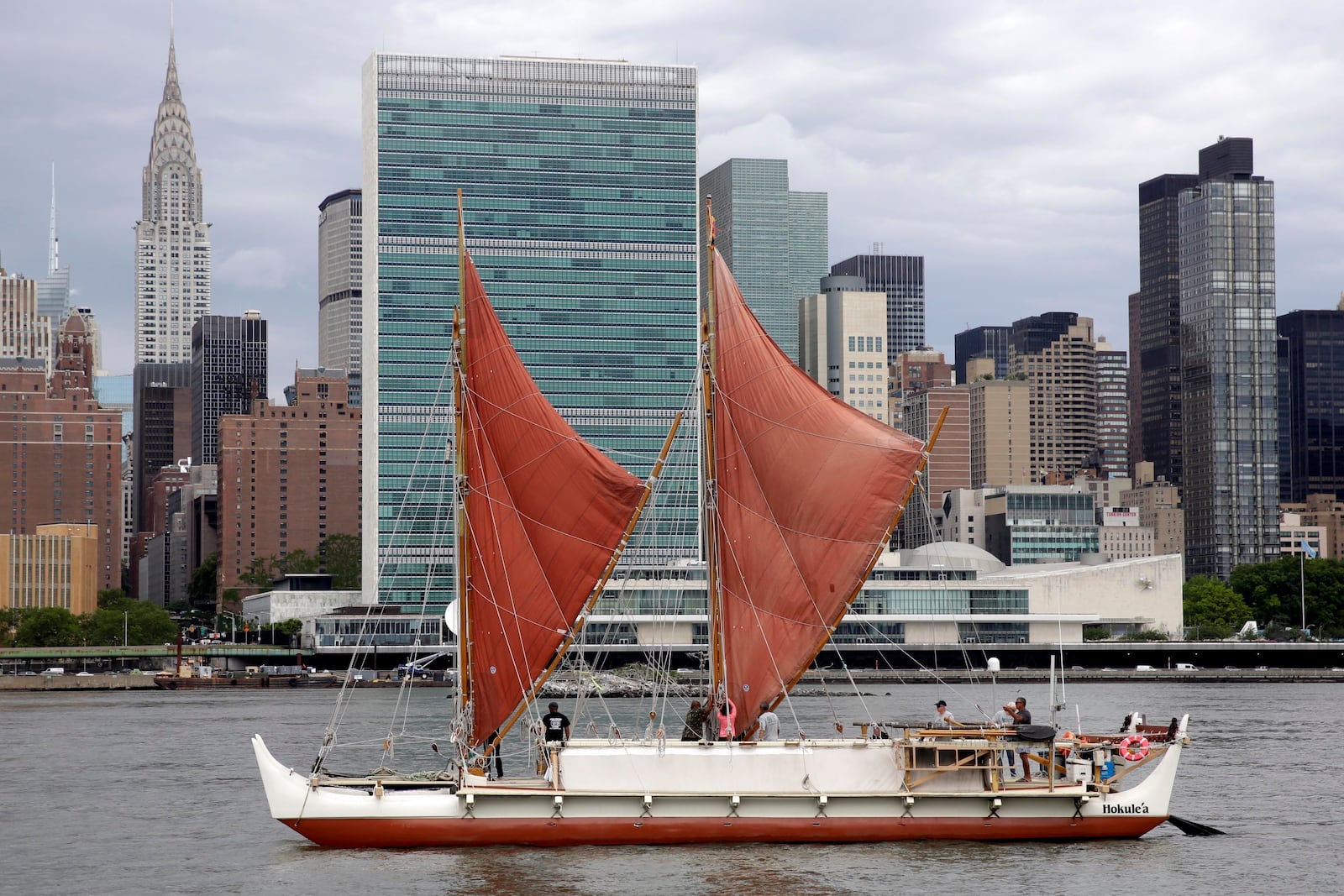 FILE - The traditional Polynesian voyaging canoe Hokulea, on an around-the-world journey, sails by the United Nations on New York's East River during the World Oceans Day observance, June 8, 2016. (AP Photo/Richard Drew, File)