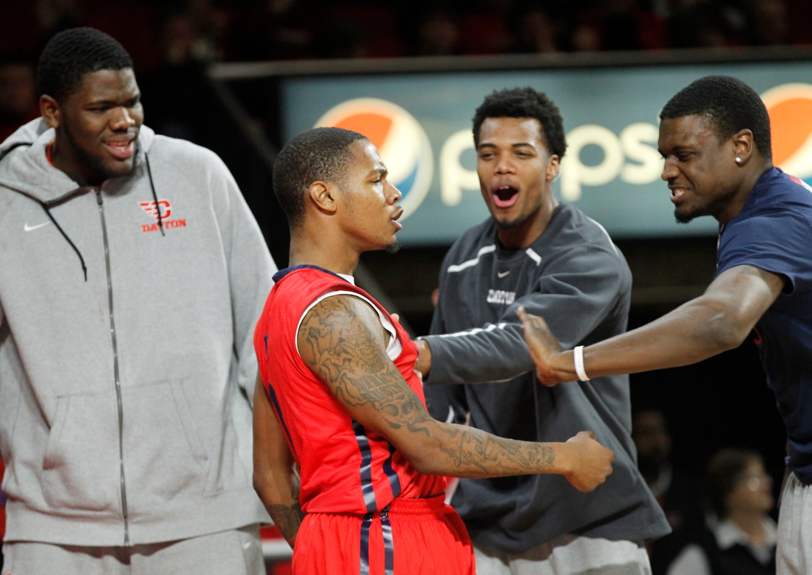 Dayton guard Ryan Bass is congratulated by Steve McElvene, left, Charles Cooke and Detwon Rogers after a layup on Wednesday, Dec. 3, 2014, at Millett Hall in Oxford.