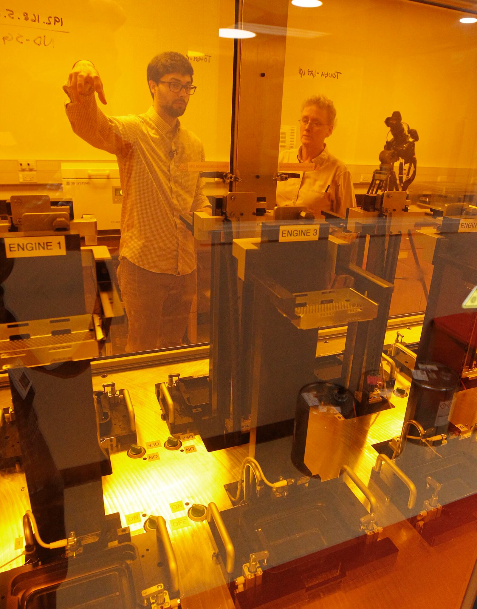 Tim Osborn, Group Leader for Additive Manufacturing Technology Development at the University of Dayton Research Institute, explains the additive manufacturing process, or 3-D printing, to Dayton Daily News writer Lynn Hulsey during a tour of the Additive Manufacturing Technology Development lab.  TY GREENLEES / STAFF