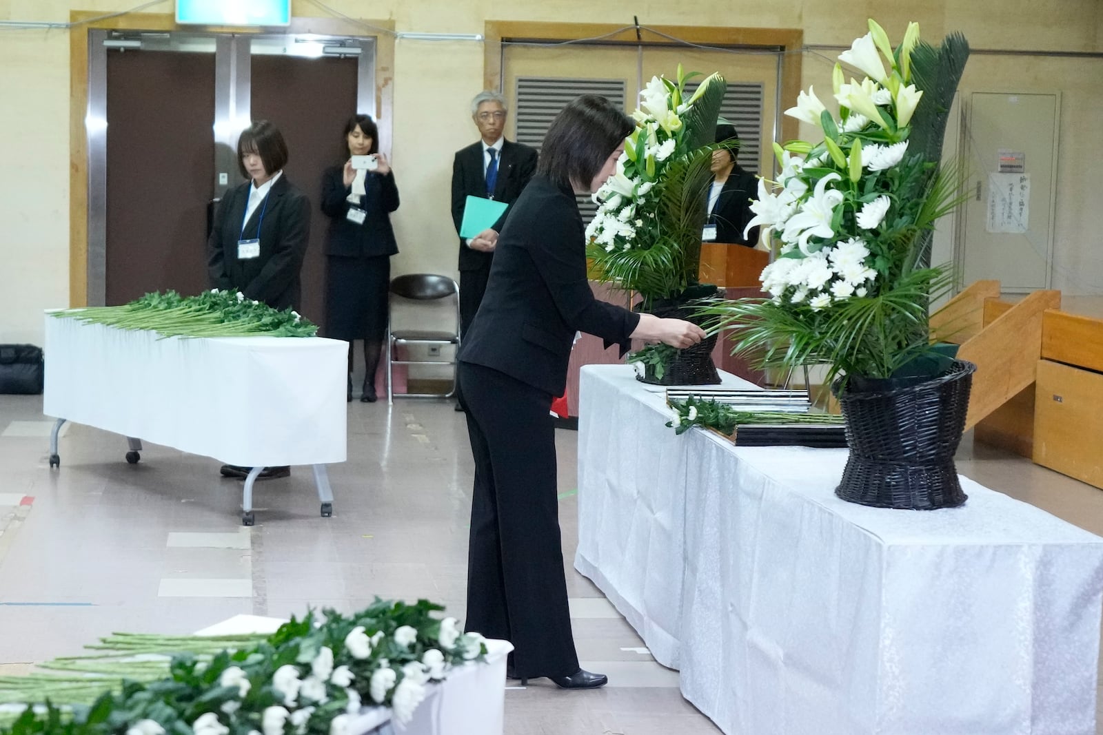 Akiko Ikuina, Parliamentary Vice-Minister for Foreign Affairs, offer a flower on behalf of the government during a memorial ceremony for the Sado Island Gold Mine in Sado, Niigata prefecture, Japan, Sunday, Nov. 24, 2024. (AP Photo/Eugene Hoshiko)