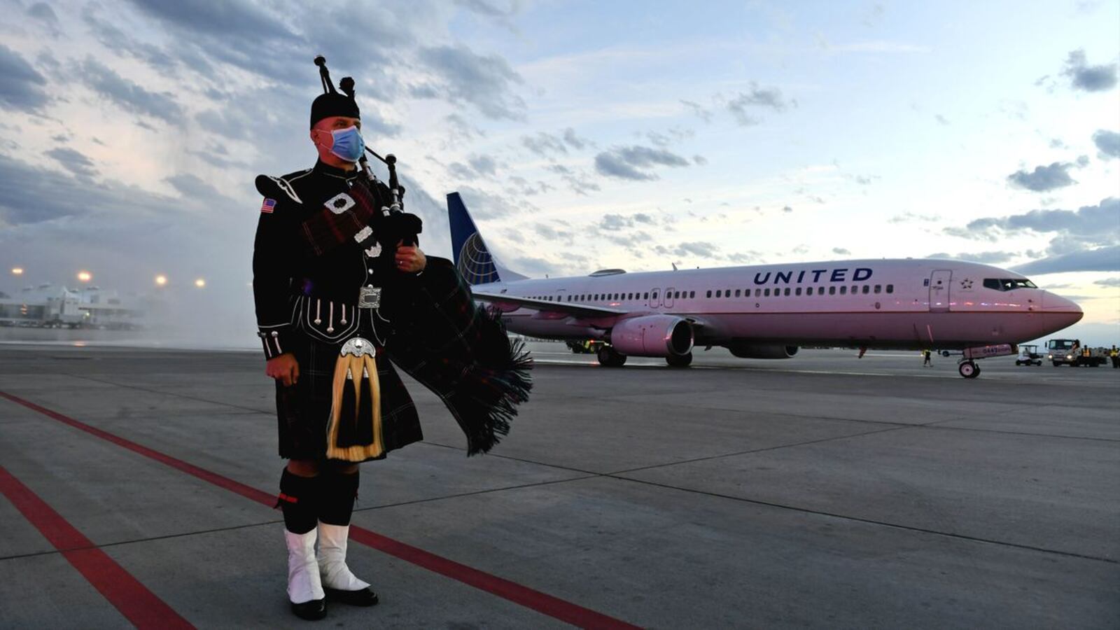 Aurora Firefighter Tom Johnson stands at attention as the flight carrying the body of paramedic Paul Cary arrives at Denver International Airport on Sunday, May 3, 2020, in Denver, Colo. Cary, 66, died Thursday, April 30, of coronavirus complications after volunteering to help combat the pandemic in New York City. (Helen H. Richardson/The Denver Post via AP)