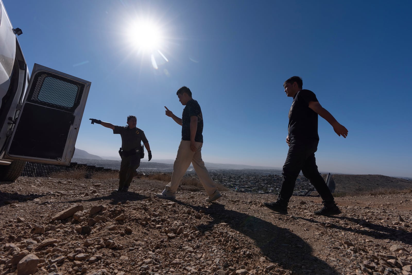 Border Patrol Agent Gutierrez directs men towards a van after they crossed the border illegally through a gap in two walls separating Mexico from the United States before turning themselves in, Thursday, Jan. 23, 2025, in San Diego. (AP Photo/Gregory Bull)