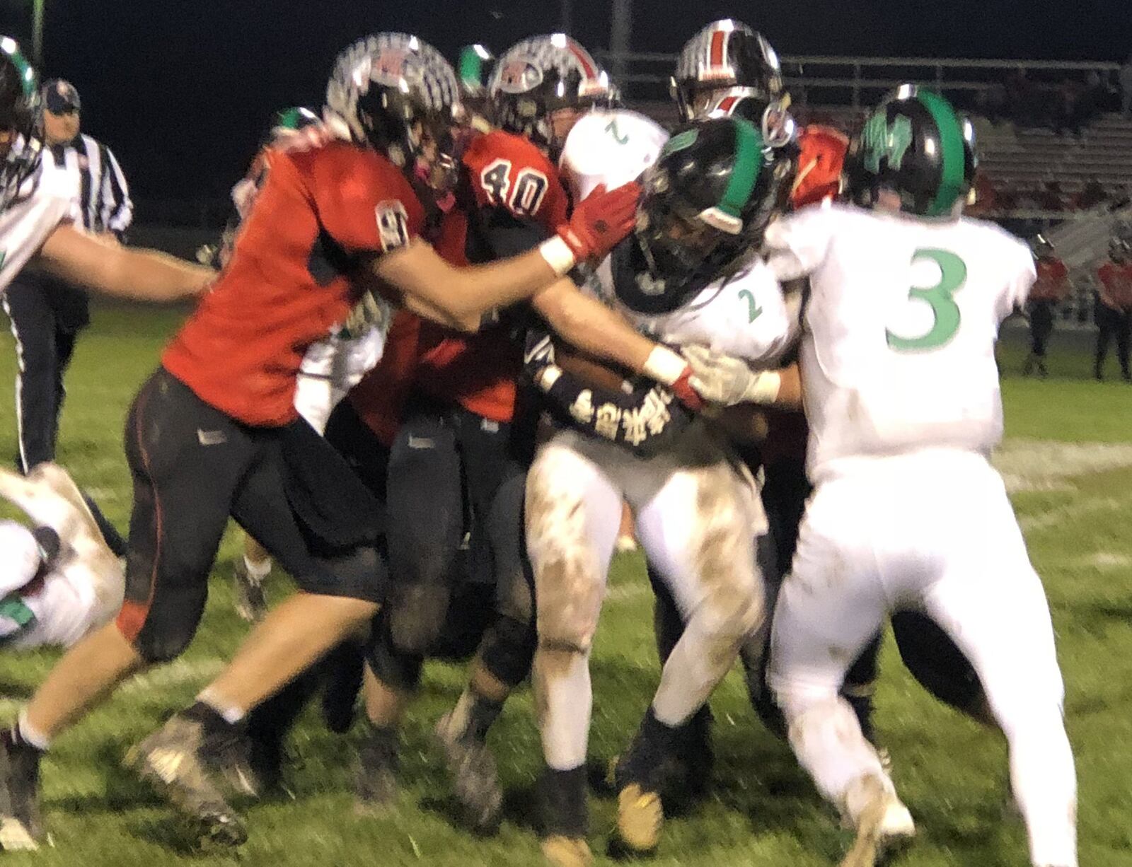 New Miami’s David Cunningham (2) runs into several Fort Loramie Redskins, including Jake Ratermann (9) and Noah Guillozet (40), during Saturday night’s Division VII, Region 28 playoff game at Redskin Stadium in Fort Loramie. The host Redskins won 41-0. RICK CASSANO/STAFF