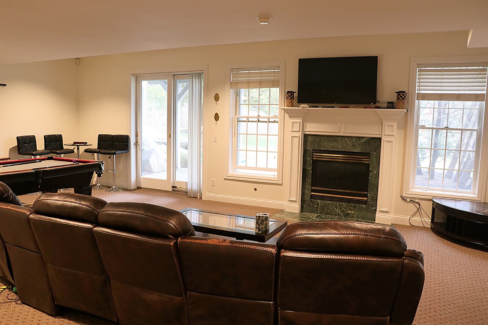 A lower-level recreation room has a gas fireplace, two daylight windows and patio doors that open to a concrete patio. Off the recreation room is a wet bar area with counter, cabinetry and sink. CONTRIBUTED PHOTO BY KATHY TYLER