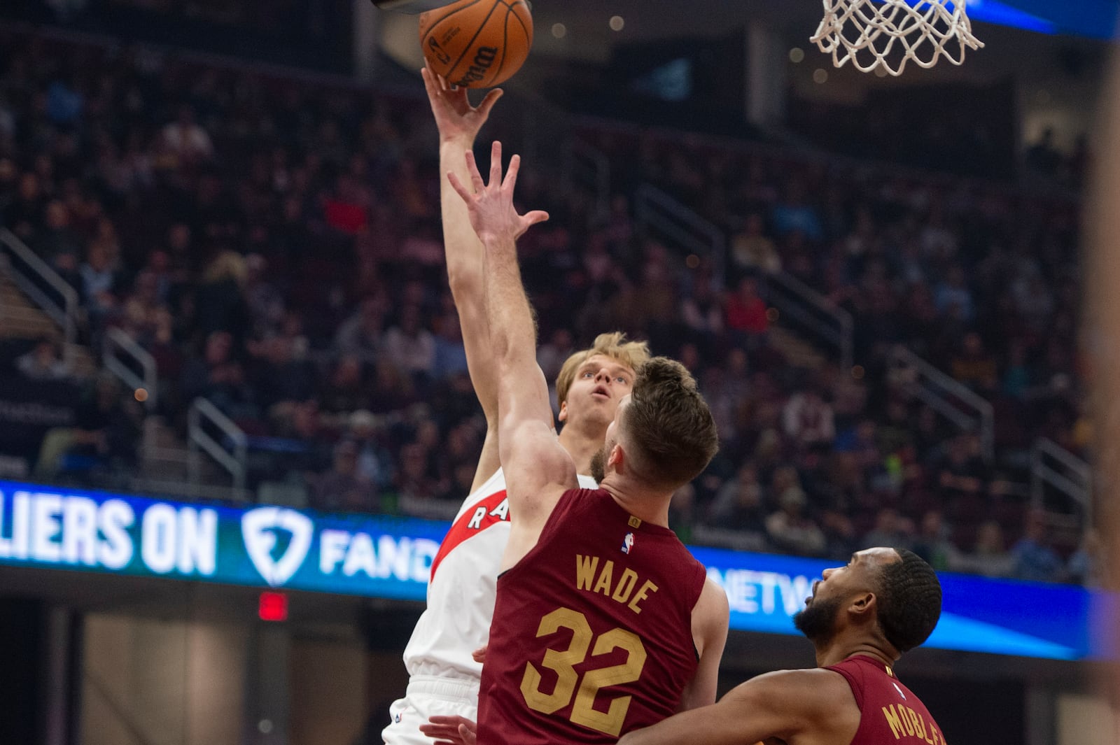 Toronto Raptors' Gradey Dick, left, shoots over Cleveland Cavaliers' Dean Wade (32) as Cavaliers' Evan Mobley, watches, looks on during the first half of an NBA basketball game in Cleveland, Thursday, Jan. 9, 2025. (AP Photo/Phil Long)