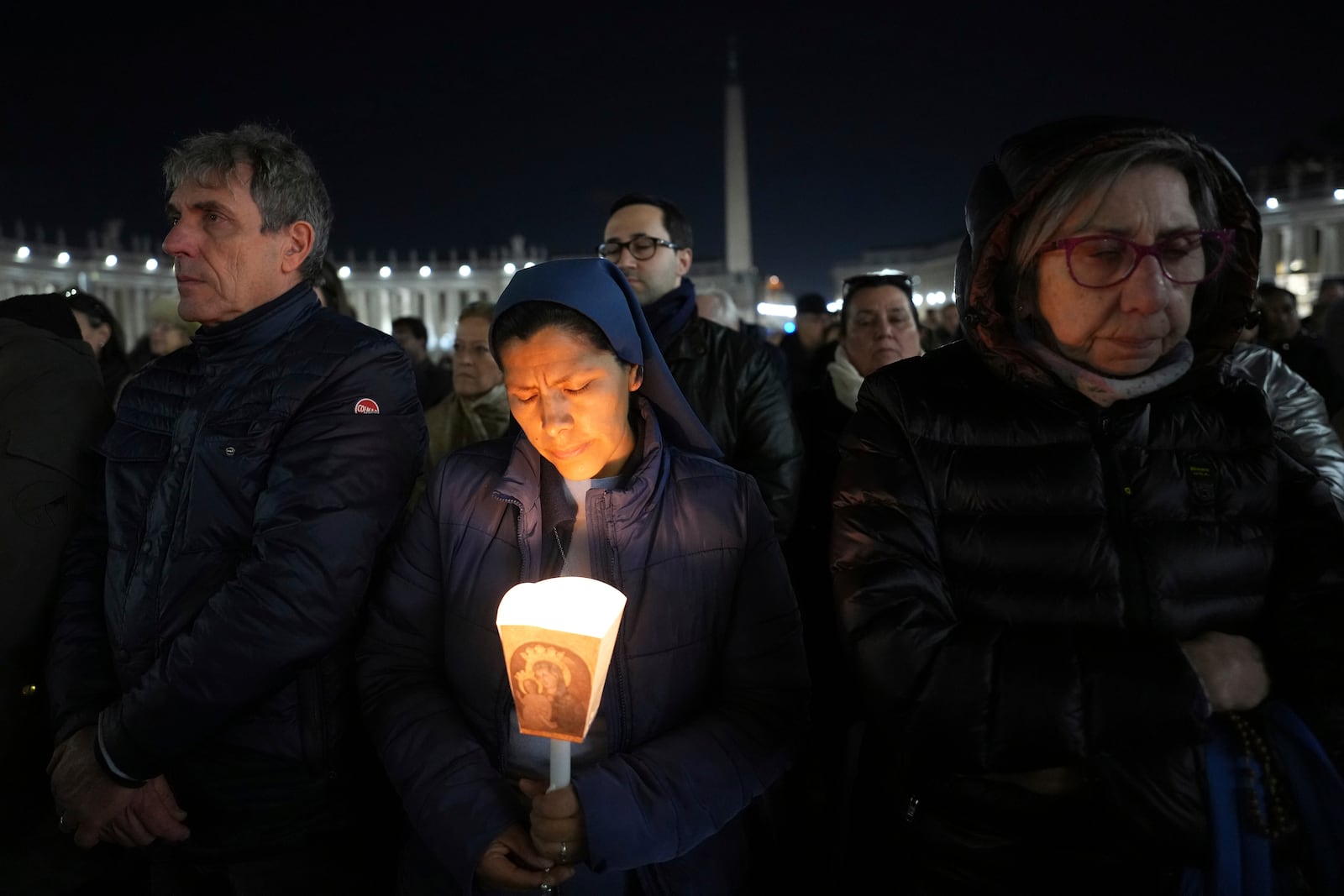 A woman holds a candle as Cardinal Robert Francis Prevost, Prefect of the Dicastery for Bishops, leads the recitation of the Holy Rosary for Pope Francis' health in St Peter's Square at the Vatican, Monday, March 3, 2025. (AP Photo/Kirsty Wigglesworth)