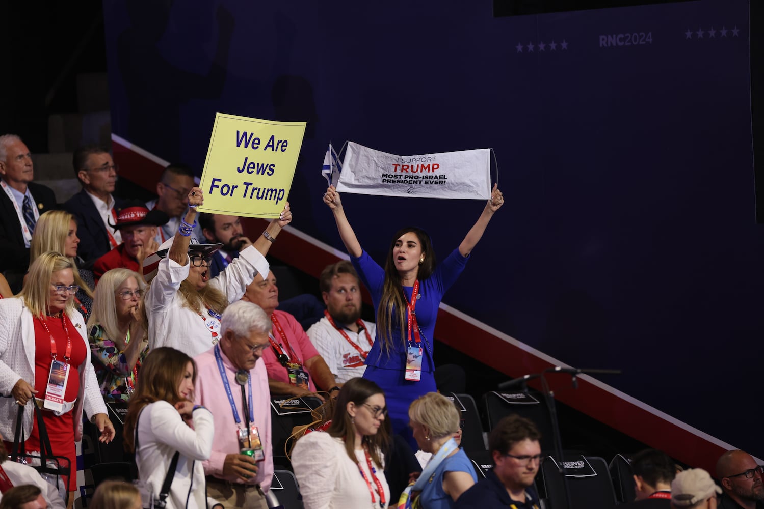 
                        Attendees hold banners as Ronen and Orna Neutra, the parents of an American-Israeli hostage in Gaza, speak on the third night of the Republican National Convention at the Fiserv Forum in Milwaukee, on Wednesday, July 17, 2024. (Maddie McGarvey/The New York Times)
                      