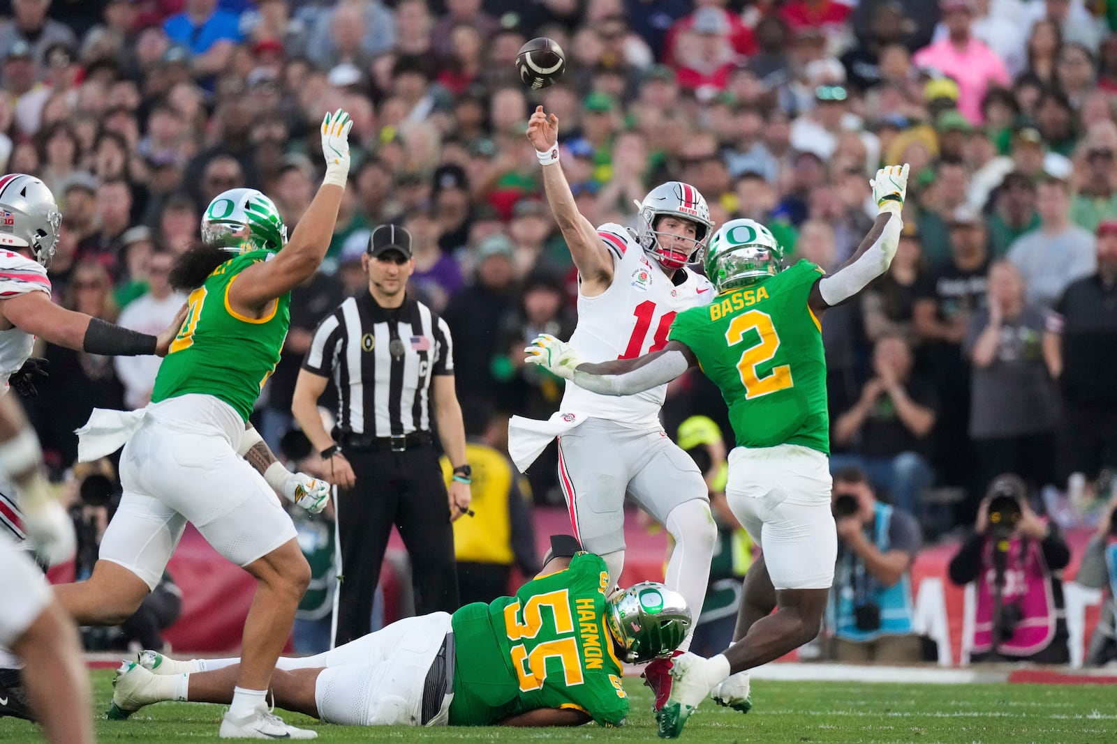 Ohio State quarterback Will Howard (18) passes under pressure by Oregon defensive lineman Derrick Harmon (55) and linebacker Jeffrey Bassa (2) during the second half in the quarterfinals of the Rose Bowl College Football Playoff, Wednesday, Jan. 1, 2025, in Pasadena, Calif. (AP Photo/Mark J. Terrill)