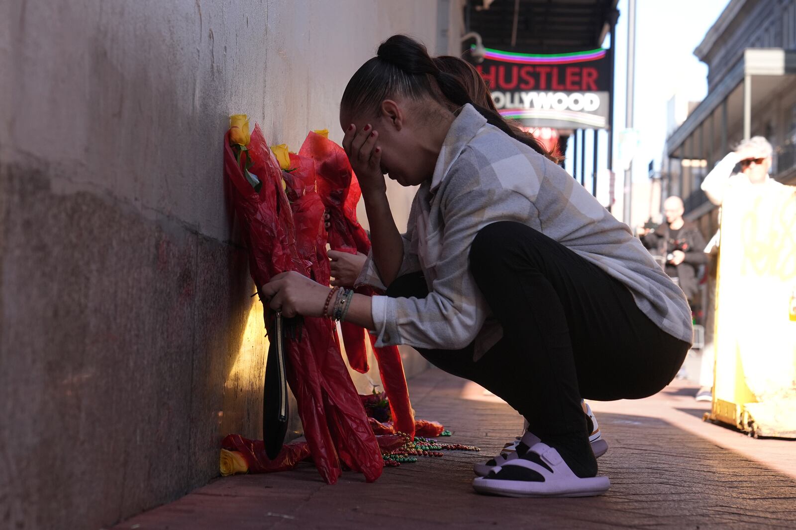 Samantha Petry places flowera at a memorial on Canal and Bourbon Street, Thursday, Jan. 2, 2025 in New Orleans. (AP Photo/George Walker IV)