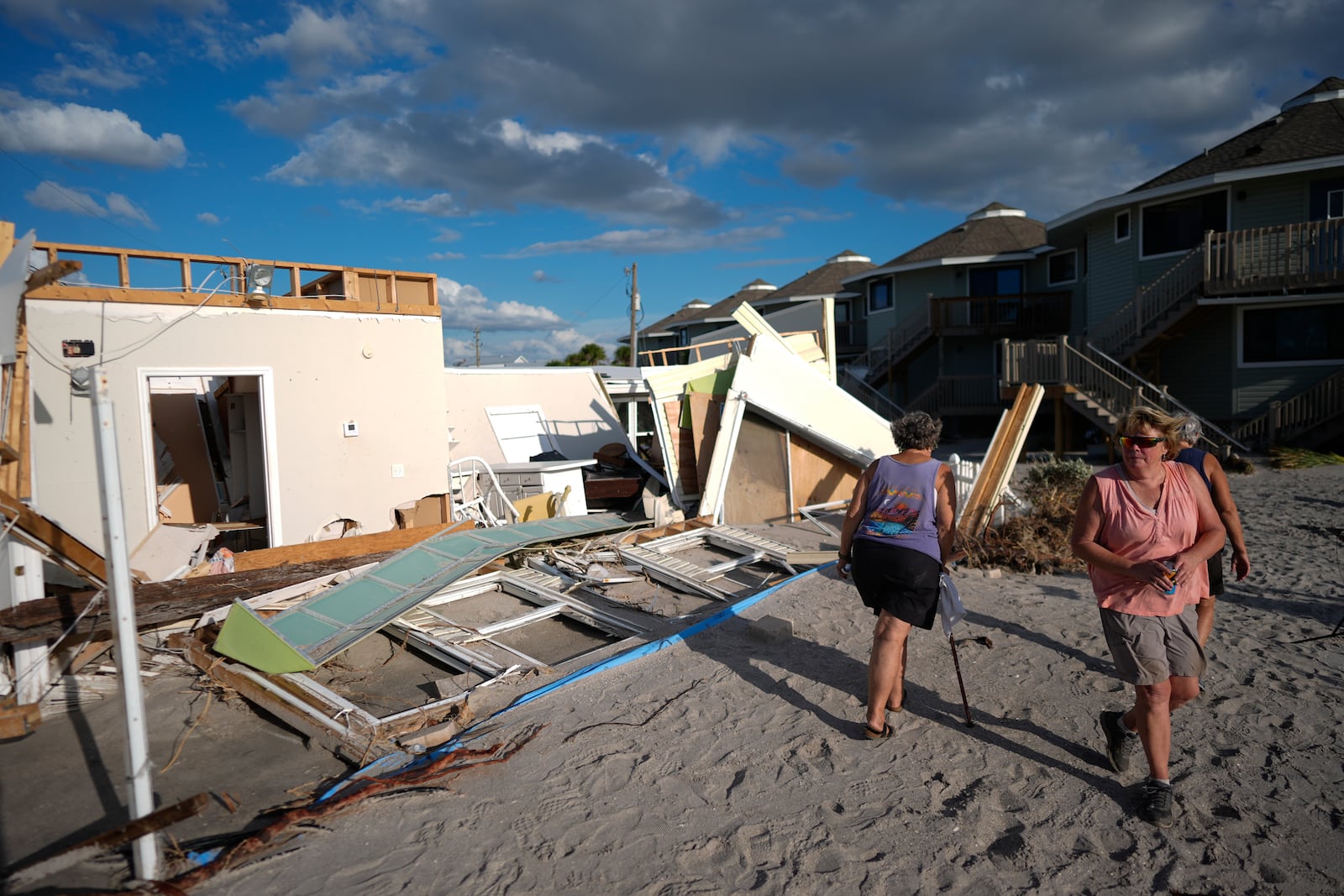 Neighbors look at what remains of a home torn apart by Hurricane Milton storm surge, in a 55+ mobile home community on Manasota Key, in Englewood, Fla., Sunday, Oct. 13, 2024. (AP Photo/Rebecca Blackwell)