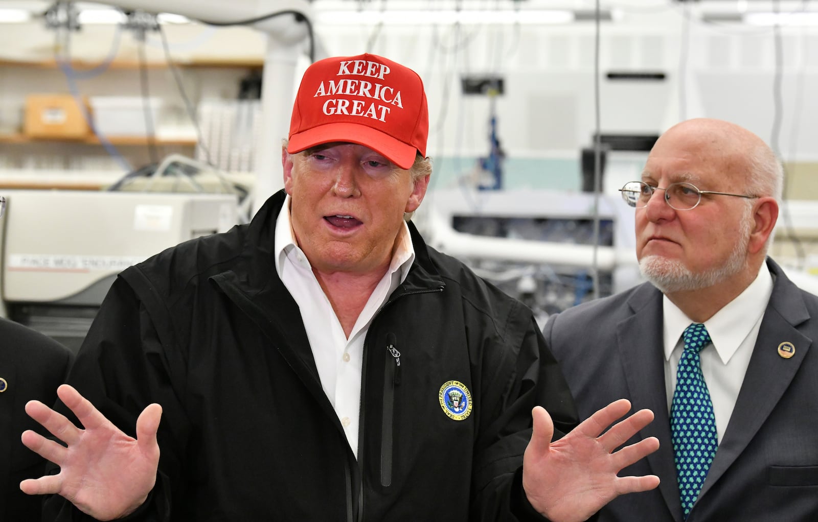 FILE - President Donald Trump speaks to members of the press as Director Robert Redfield, right, looks at the headquarters of the Centers for Disease Control and Prevention in Atlanta, March 6, 2020. (Hyosub Shin/Atlanta Journal-Constitution via AP, file)