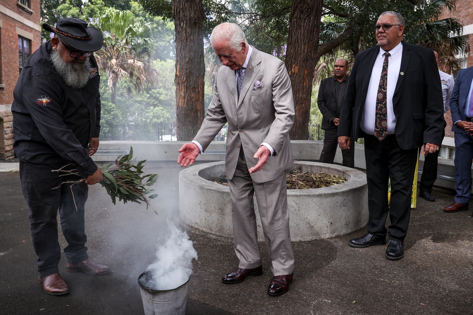 King Charles III, center, participates in a traditional smoking ceremony conducted by community representatives from the Gadigal people of the Eora Nation during a visit to the National Centre of Indigenous Excellence on Tuesday Oct. 22, 2024 in Sydney, Australia. (Lisa Maree Williams/Pool Photo via AP)