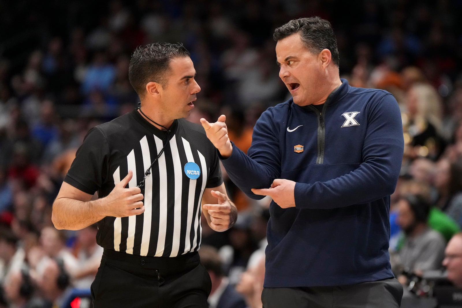 Xavier head coach Sean Miller, right, speaks with an official during the first half of a First Four college basketball game against Texas in the NCAA Tournament, Wednesday, March 19, 2025, in Dayton, Ohio. (AP Photo/Jeff Dean)