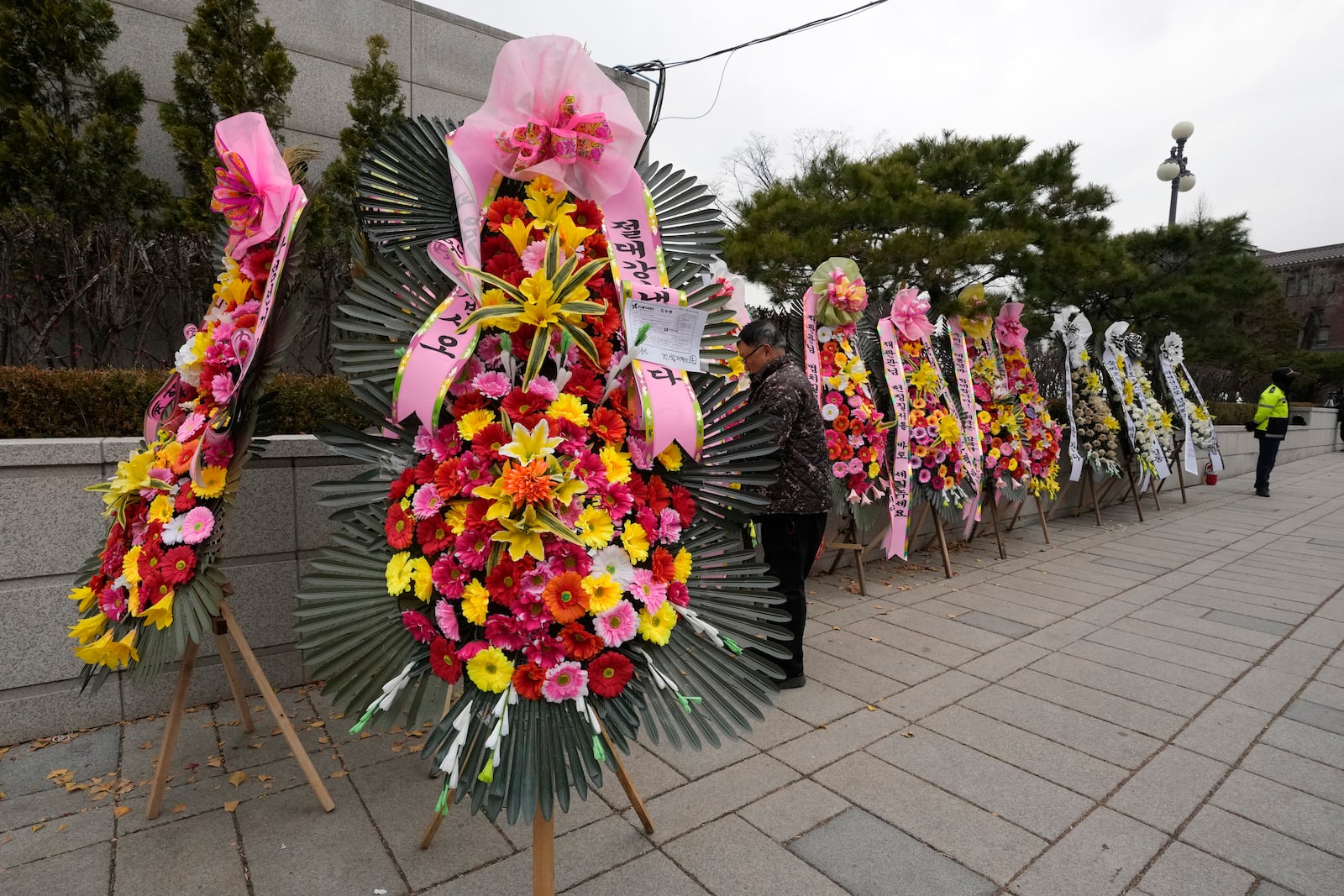 A worker places a wreath sent by supporters for impeached South Korean President Yoon Suk Yeol outside the Constitutional Court in Seoul, South Korea, Monday, Dec. 16, 2024. (AP Photo/Ahn Young-joon)