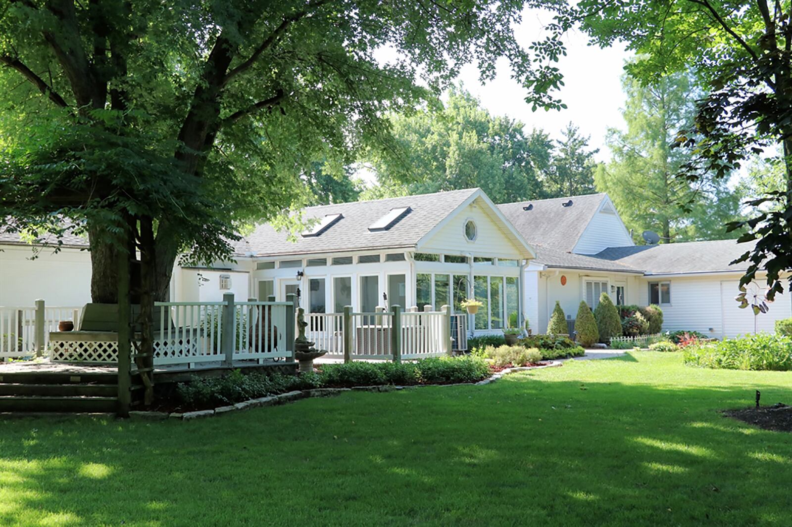 The fenced back yard offers shady areas, a putting green, a wooden deck with a bench seat that wraps around a mature tree, a paver-brick patio and walking paths, a water feature and a small pond. CONTRIBUTED PHOTO BY KATHY TYLER