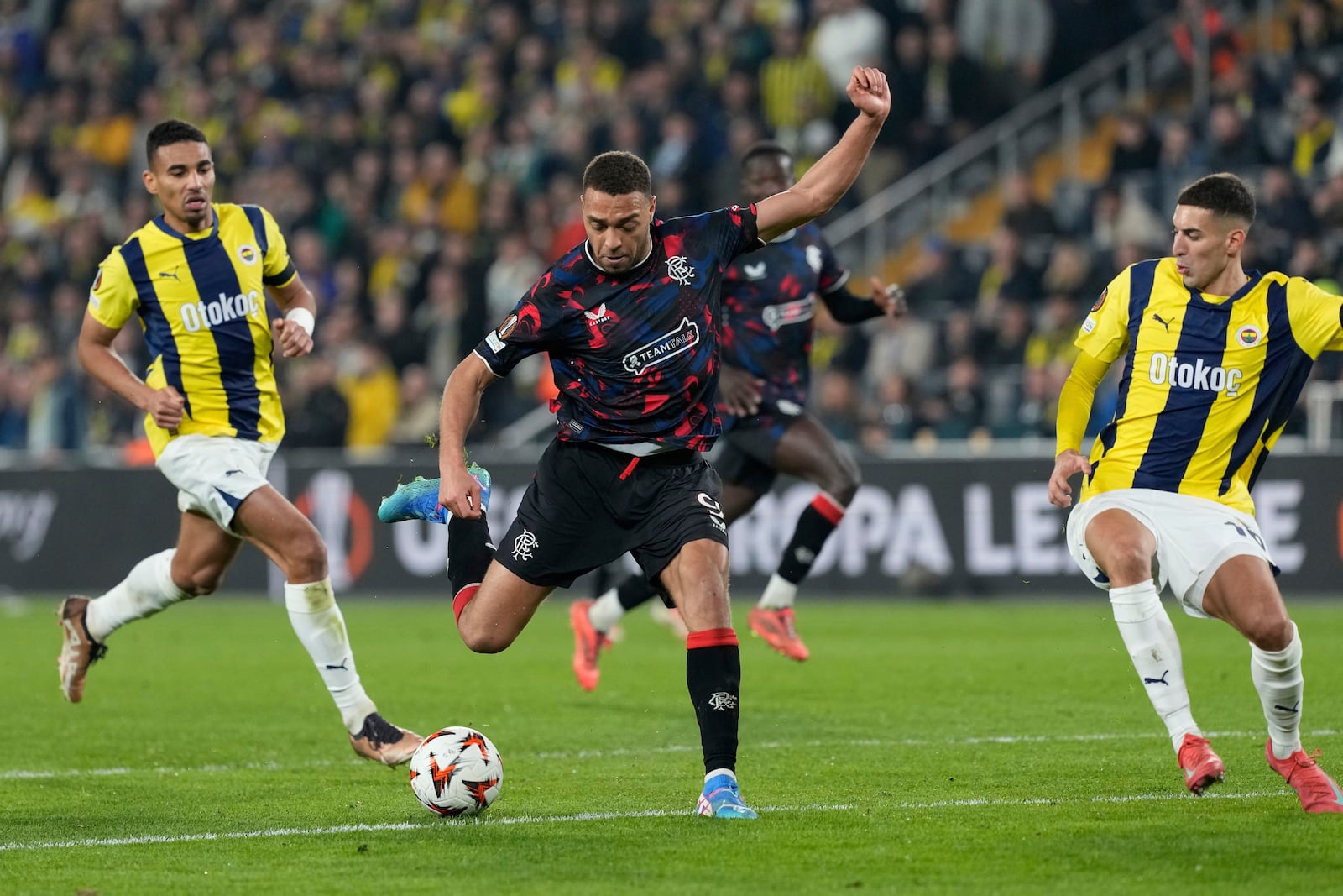 Rangers' Cyriel Dessers, center, attempts a shot at goal in front of Fenerbahce's Mert Muldur during the Europa League round of 16 first leg soccer match between Fenerbahce and Rangers at Sukru Saracoglu stadium in Istanbul, Turkey, Thursday, March 6, 2025. (AP Photo/Khalil Hamra)