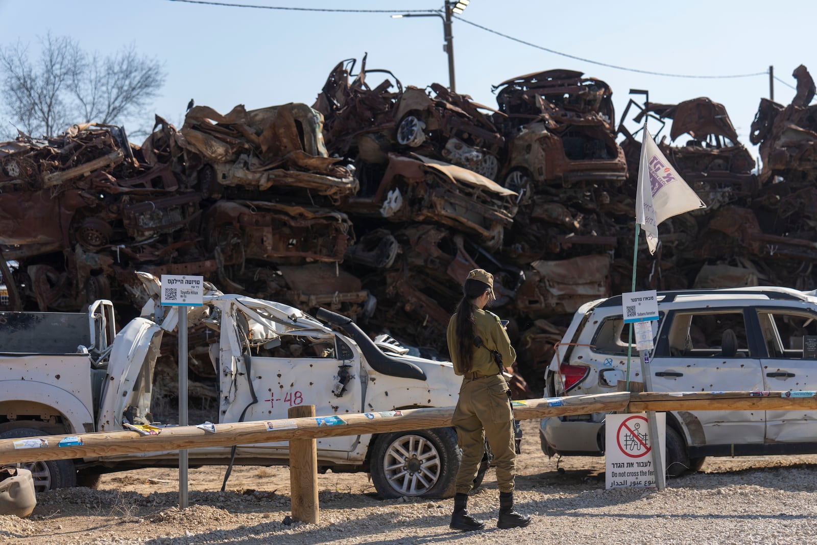 An Israeli soldier looks at charred vehicles burned in the Oct. 7 , 2023, cross-border attacks by Hamas militants outside the town of Netivot, southern Israel, Monday, Jan. 13, 2025. (AP Photo/Ariel Schalit)