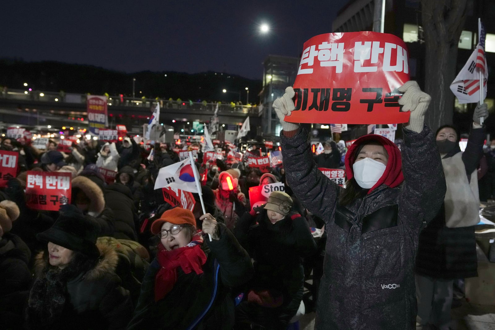 Supporters of impeached South Korean President Yoon Suk Yeol stage a rally to oppose a court having issued a warrant to detain Yoon, as police offices stand guard near the presidential residence in Seoul, South Korea, Friday, Jan. 3, 2025. The sign reads "Oppose Impeachment." (AP Photo/Lee Jin-man)