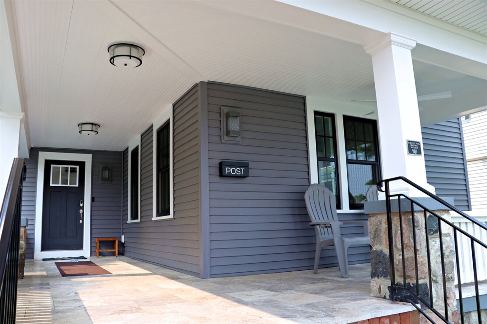 The wrap-around front porch has a metal roof, stone-tile floor and an updated railing within the stone accents.