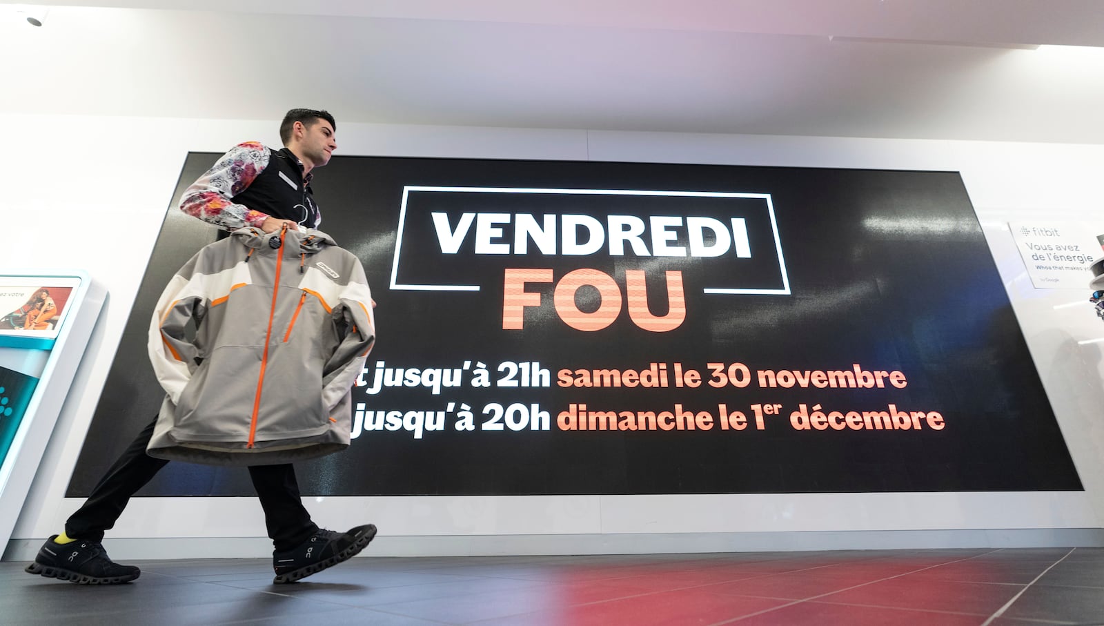 A Sport Expert's employee walks past a sign advertising Black Friday sales in Montreal on Friday, Nov. 29, 2024. (Christinne Muschi /The Canadian Press via AP)