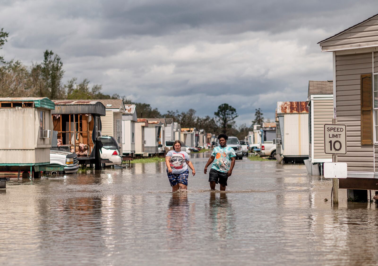 People walk through a flooded section of Wheel Estates Mobile Home Park in LaPlace, La., on Monday, Aug. 30, 2021. Hurricane Ida made landfall near Port Fourchon, La., on Sunday, the 16th anniversary of Hurricane Katrina, slamming the southeastern coast with dangerous winds and storm surge and leaving most residents without power. (Emily Kask/The New York Times)