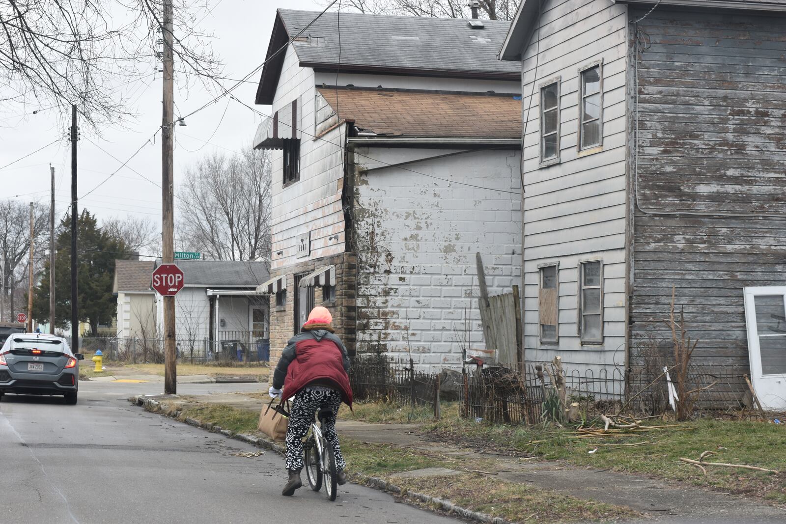 A woman rides her bike in East Dayton on a block with multiple tax-delinquent properties, including one on the corner that owes more than $24,000 in back taxes. CORNELIUS FROLIK / STAFF