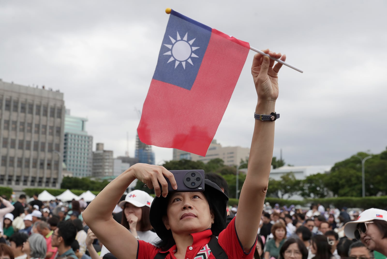 A person poses with Taiwan's national flag for a photo during National Day celebrations in front of the Presidential Building in Taipei, Taiwan, Thursday, Oct. 10, 2024. (AP Photo/Chiang Ying-ying)