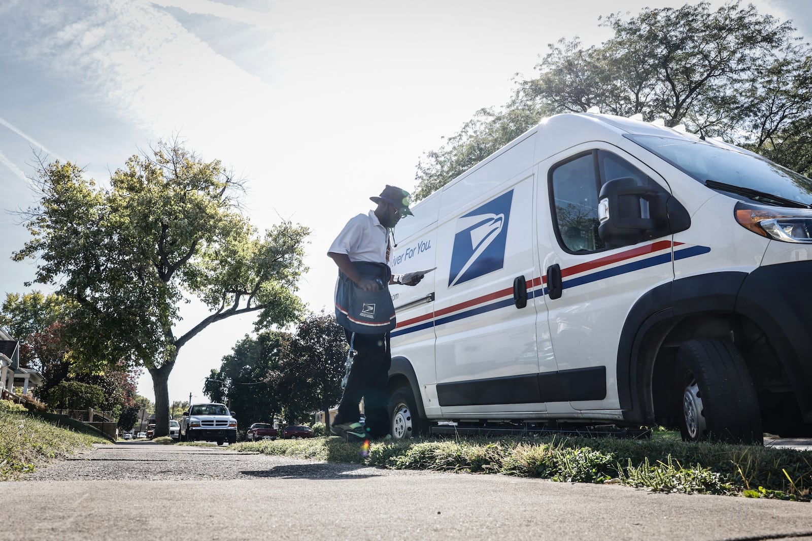 A mail carrier walks back to his truck after picking up and delivering mail on the eastside of Dayton. JIM NOELKER/STAFF