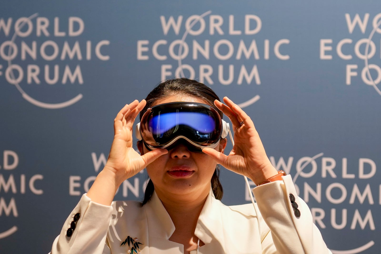 A woman uses virtual reality glasses the Annual Meeting of World Economic Forum in Davos, Switzerland, Wednesday, Jan. 22, 2025. (AP Photo/Markus Schreiber)