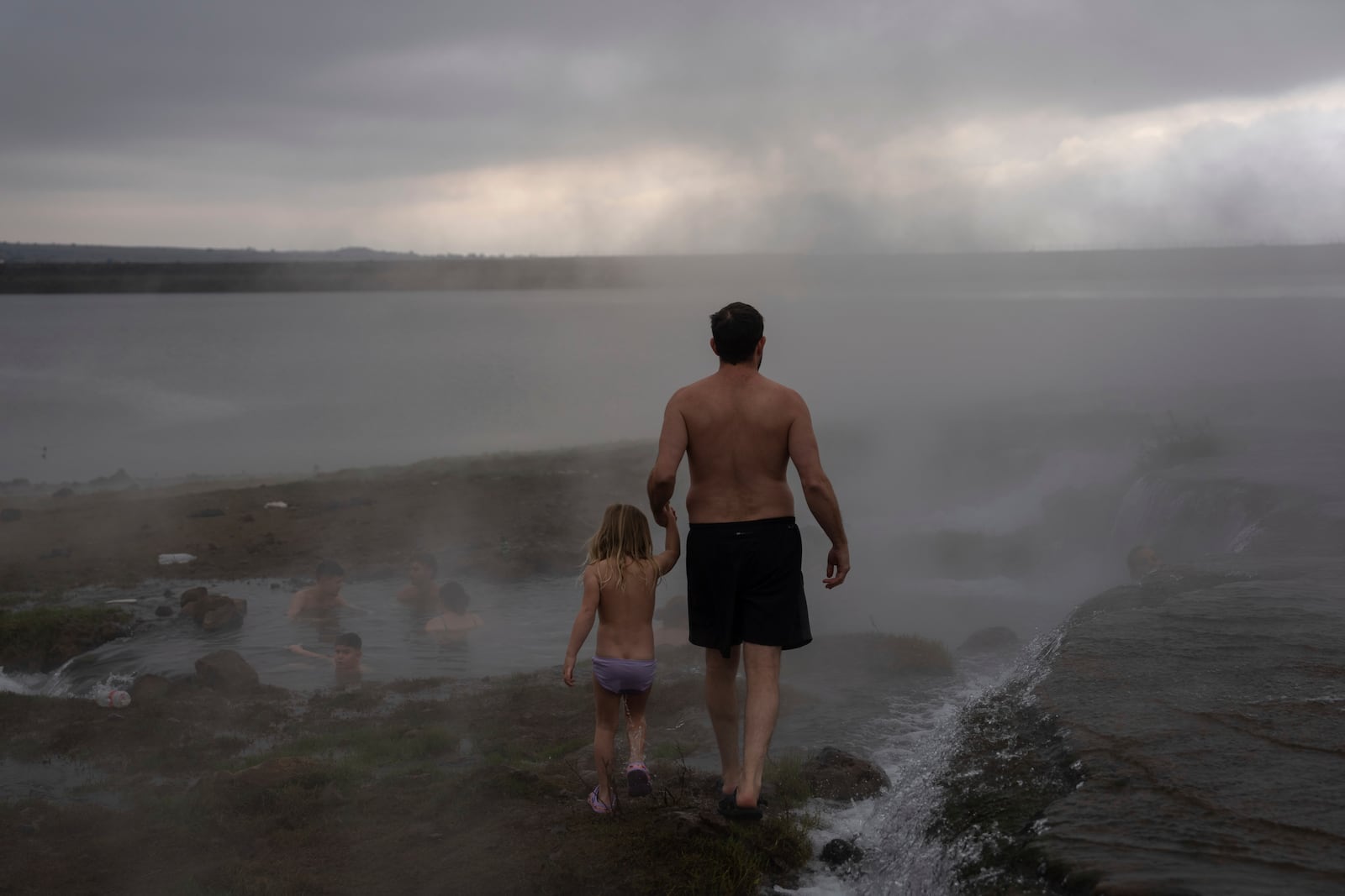 Israeli residents bathe in a hot water pool coming from a drilling project which exposed a subterranean hydrothermal spring near Mount Bental in the Israeli-controlled Golan Heights, on the first day of the ceasefire between Israel and Hezbollah, Wednesday, Nov. 27, 2024. (AP Photo/Ohad Zwigenberg)