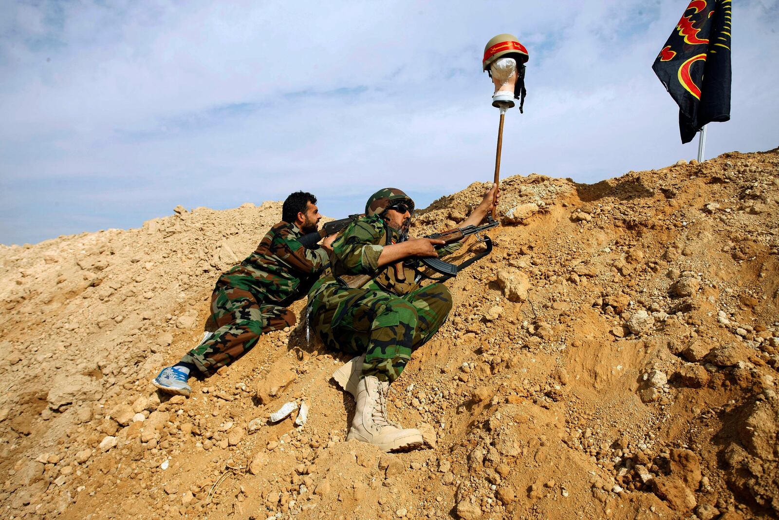 FILE - In this Nov. 22, 2013, file photo, Iraqi and Lebanese Shiite fighters from a group called the Hussein Brigade use a helmet to draw a sniper into view during clashes between the Sunni-dominated Free Syrian Army and Syrian soldiers loyal to Syria's President Bashar Assad, supported by Iraqi and Lebanese Shiite fighters, in the town of Hejeira, which Syrian troops captured, in the countryside of Damascus, Syria. (AP Photo/Jaber al-Helo, File)