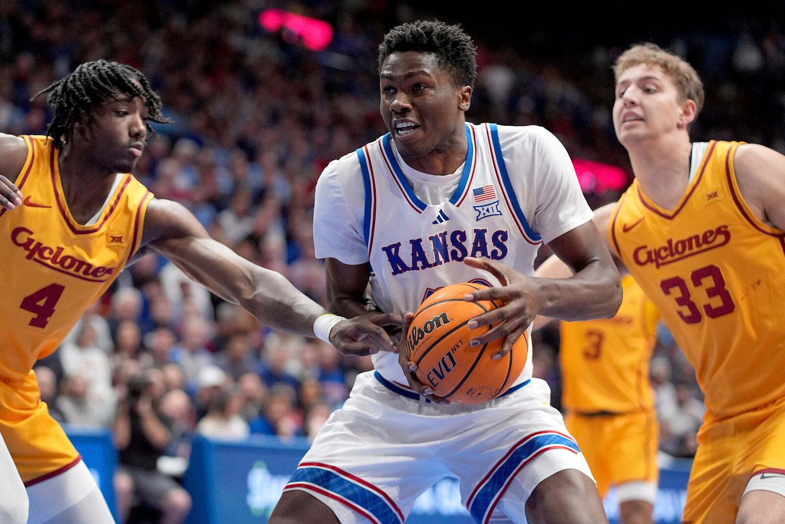 Kansas forward Flory Bidunga, center, looks to pass under pressure from Iowa State guard Demarion Watson (4) and forward Brandton Chatfield (33) during the first half of an NCAA college basketball game, Monday, Feb. 3, 2025, in Lawrence, Kan. (AP Photo/Charlie Riedel)