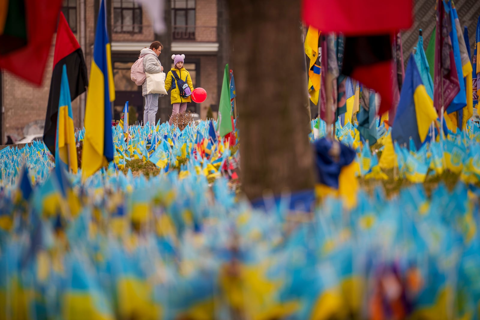 A child holds a balloon while looking at a memorial for soldiers who perished in the war in Kyiv, Ukraine, Thursday, March 14, 2024. (AP Photo/Vadim Ghirda)