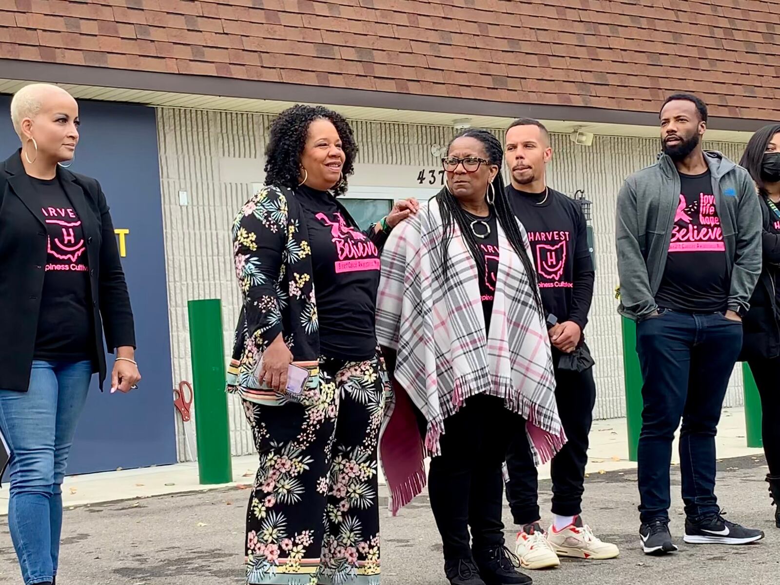 CEO Ariane Kirkpatrick places a hand on the shoulder of her sister, COO Amonica Davis, at the grand opening of Harvest of Beavercreek, surrounded by family members and employees.