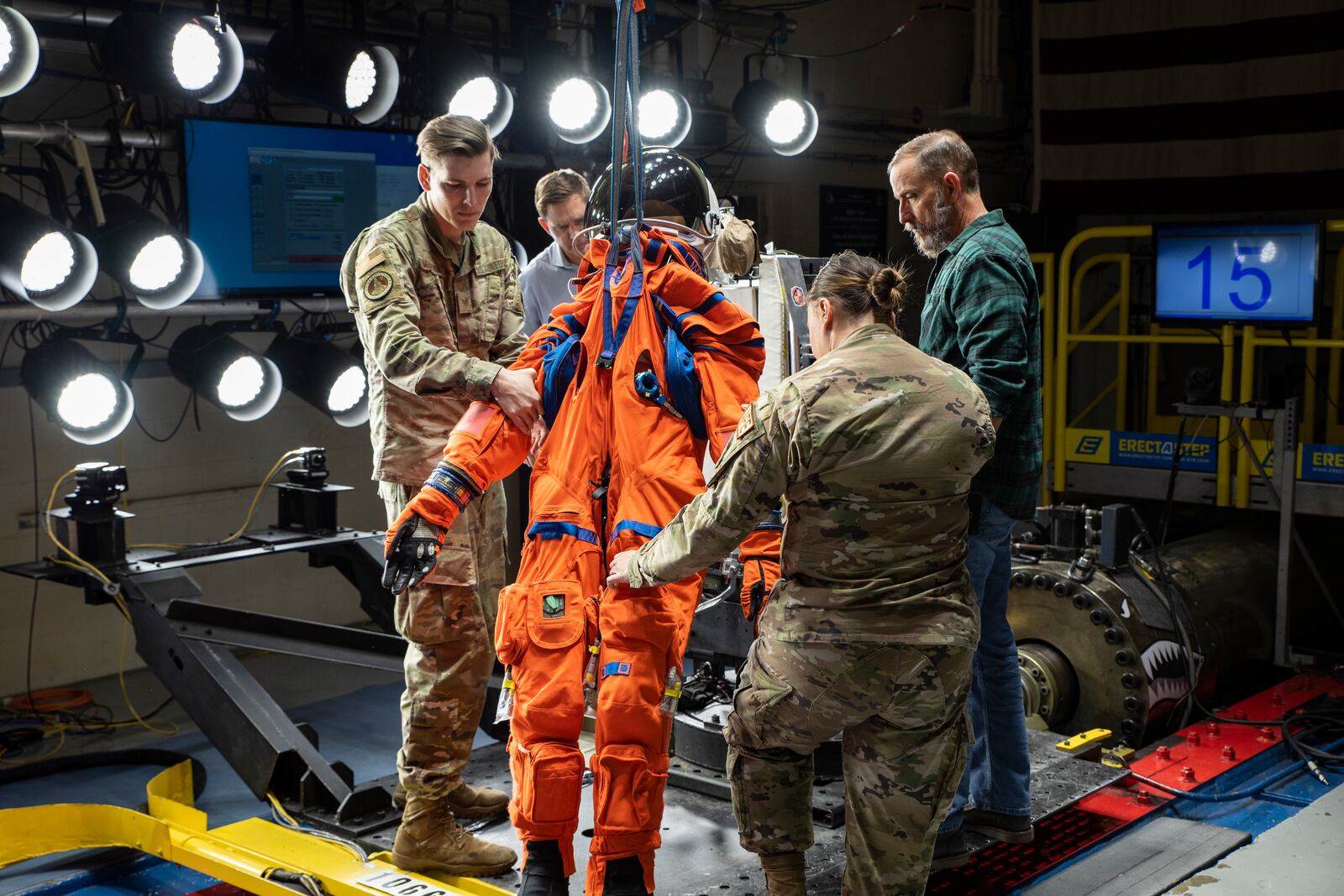 The Air Force Research Laboratory, or AFRL, and NASA staff hoist Campos, a fire and rescue training manikin, into the seat at the sled test facility at Wright-Patterson Air Force Base, April 17, 2023. AFRL and NASA, along with other industry partners, such as Lockheed Martin, tested the most current iteration of an astronaut crew seat and flight suit that will be used on the Orion space capsule during the next mission to the moon under the Artemis Program. The manikin used in the testing was Campos, named after the legendary Arturo Campos, an electrical engineer who was instrumental to saving the Apollo 13 crew. Campos is accurately weighed and has the appropriate density of a human for testing. (U.S. Air Force photo / Rick Eldridge)