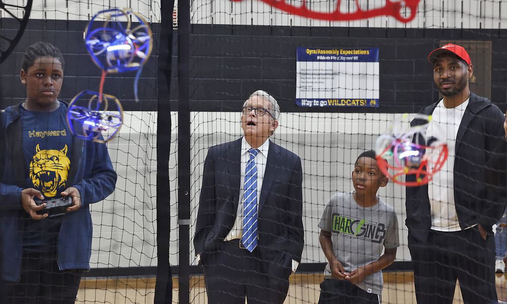 Gov. Mike DeWine and former Ohio State football star Braxton Miller watch as Jamir Rolls, a member of the Hayward Middle School drone soccer team, operates his drone Tuesday, May 7, 2024, in Springfield. The drone soccer team recently returned from Washington, D.C., where they competed in the National Drone Soccer Championships. Hayward was the first school in Ohio to have a drone soccer team. BILL LACKEY/STAFF