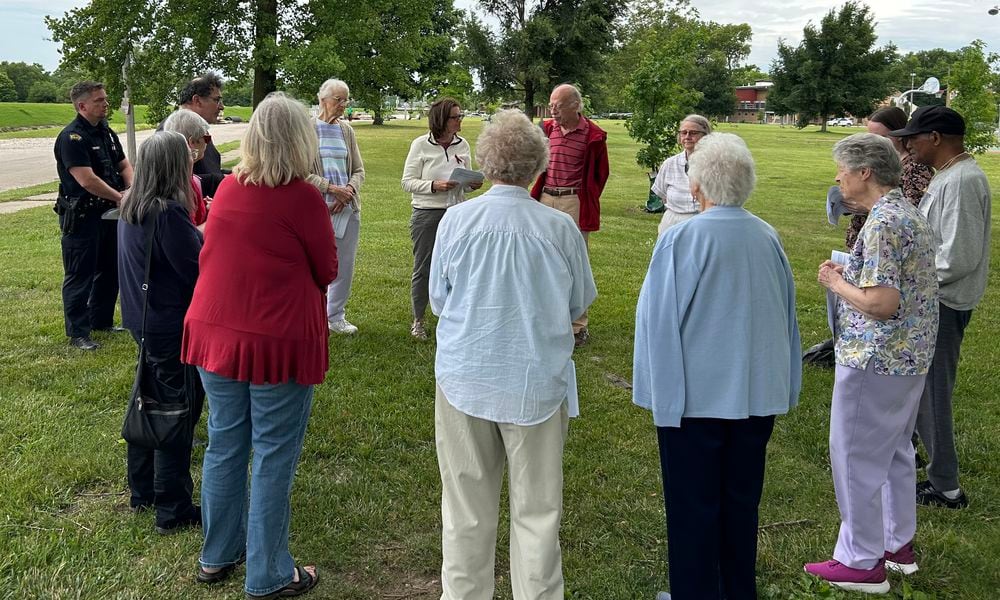 Two Dayton police officers join a group of Dayton-area residents holding a prayer vigil for homicide victims June 8, 2024, at McIntosh/Riverview Park in Dayton. JEREMY P. KELLEY / STAFF