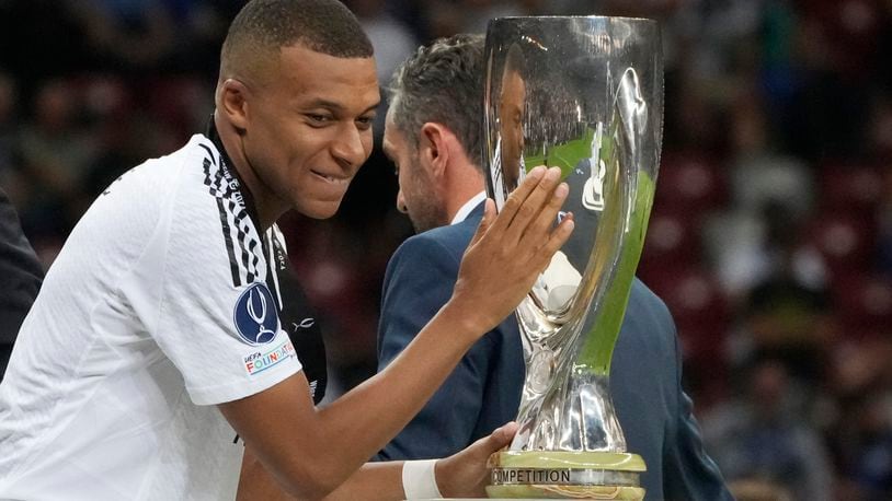 Real Madrid's Kylian Mbappe touches the trophy during the medal ceremony for the UEFA Super Cup Final soccer match between Real Madrid and Atalanta at the Narodowy stadium in Warsaw, Poland, Wednesday, Aug. 14, 2024. (AP Photo/Czarek Sokolowski)