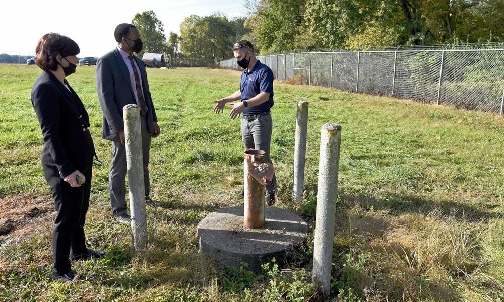 In this 2020 photo, Treva Bashore, restoration program manager, 88th Air Base Wing Civil Engineer Center (left), Amir Mott, deputy director, 88th Civil Engineer Group (center), and Dan Casey, lead field operations engineer, discuss a monitoring well at the fire training area of Wright-Patterson Air Force Base. (U.S. Air Force photo by Ty Greenlees)