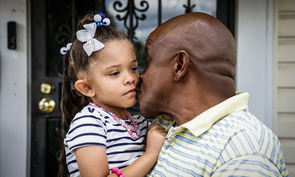 Quintinn Hardwick kisses his five-year-old daughter Arianna Alexis Hardwick before walking to the bus stop in their Dayton neighborhood on June 7, 2024. Hardwick participates in and volunteers with Montgomery County's Father Initiative programs. JIM NOELKER/STAFF