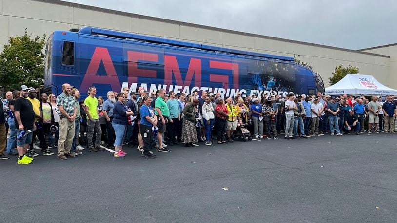 Trimble employees gather for a photo as the Association of Equipment Manufacturers tour bus stopped by the company's Huber Heights manufacturing complex Monday. THOMAS GNAU/STAFF