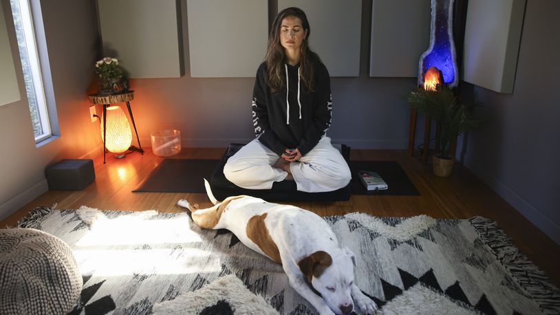 Headspace meditation teacher, Rosie Acosta, meditates in her studio with her dog Monday, Sept. 30, 2024, in Woodland Hills, Calif. (AP Photo/Jessie Alcheh)