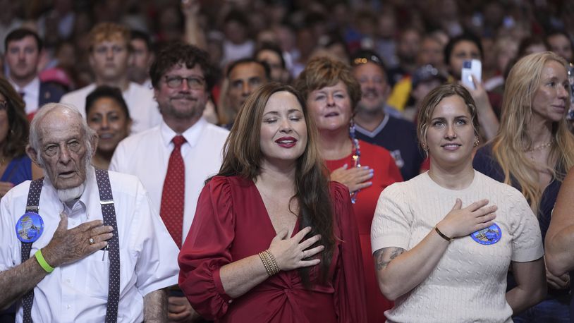 Audience members stand to say the Pledge of Allegiance before Republican presidential candidate former President Donald Trump arrives to deliver remarks on the tax code, and manufacturing at the Johnny Mercer Theatre Civic Center, Tuesday, Sept. 24, 2024, in Savannah, Ga. (AP Photo/Evan Vucci)