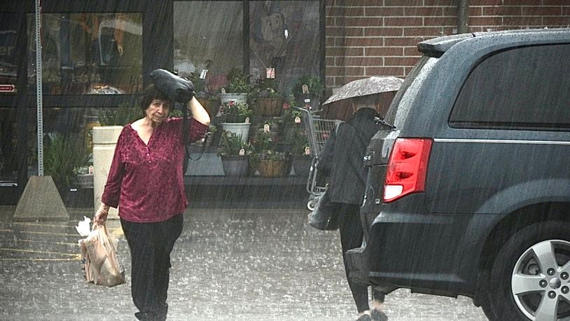 Shoppers make their way to their cars during heavy rainfall Wednesday, April 5, 2023, at the Kroger marketplace in Beavercreek. MARSHALL GORBY \STAFF