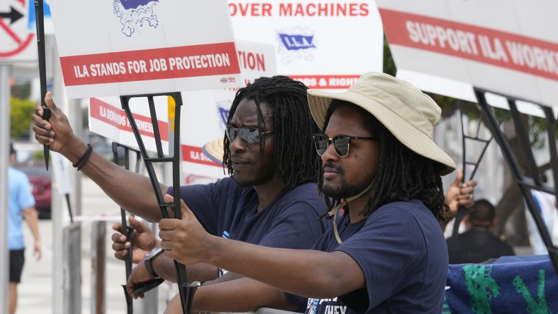 Dockworkers from Port Miami display signs at a picket line, Thursday, Oct. 3, 2024, in Miami. (AP Photo/Marta Lavandier)