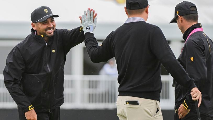 International team member Jason Day, of Australia, left, high-fives teammate Sungjae Im, of South Korea, on the putting green during practice at the Presidents Cup golf tournament, Monday, Sept. 23, 2024 in Montreal. (Christinne Muschi/The Canadian Press via AP)