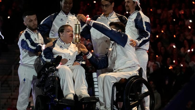 A French paralympic athlete extinguishes the lantern after passing the Olympic flame on to the U.S. during the closing ceremony of the 2024 Paralympics under the rain, Sunday, Sept. 8, 2024, in Paris, France. (AP Photo/Michel Euler)