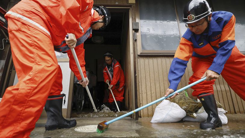 Firefighters help clean up floodwater out of a house in Ogaki, central Japan, Saturday, Aug. 31, 2024, following a tropical storm in the area. (Natsumi Yasumoto/Kyodo News via AP)